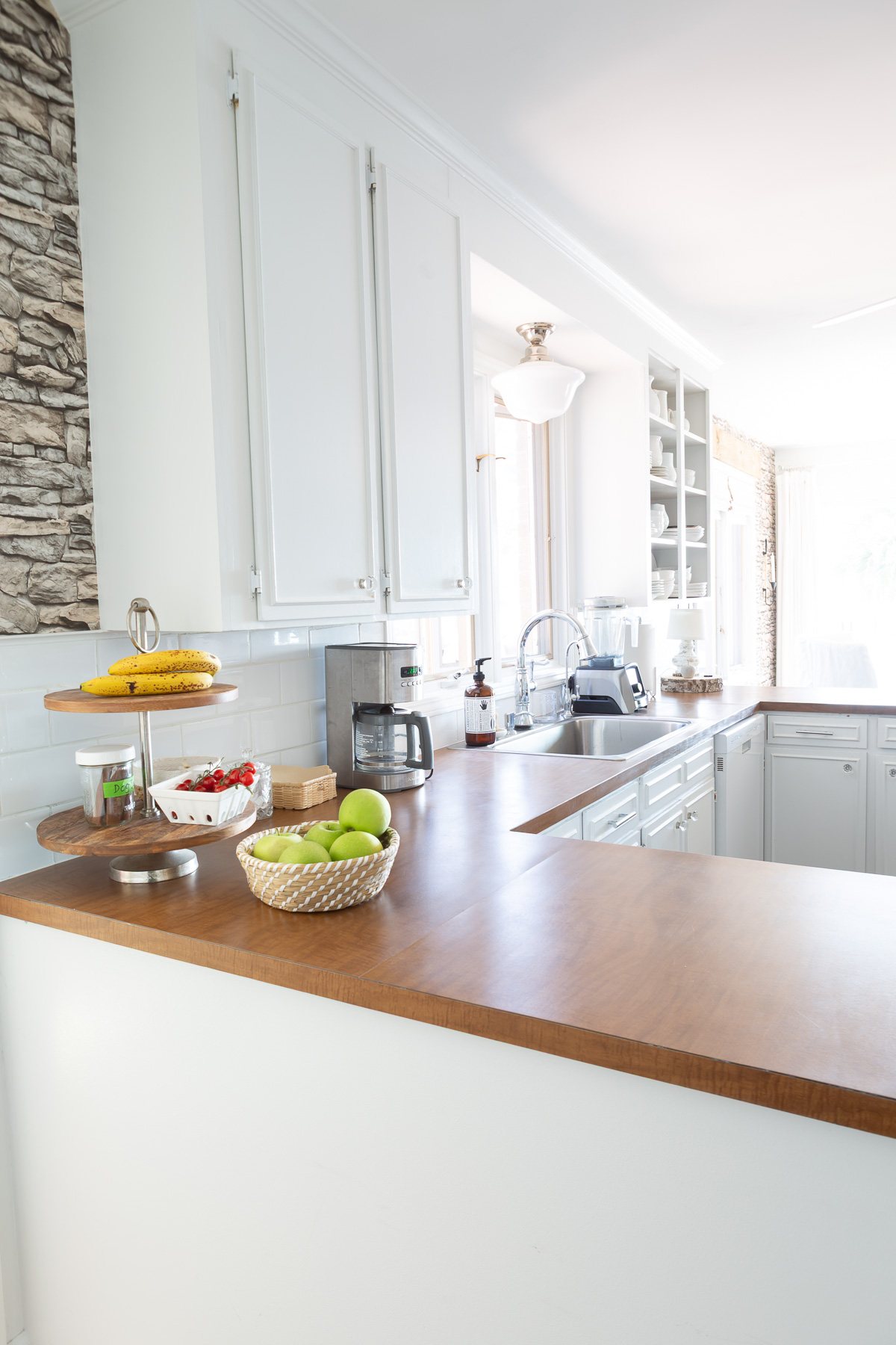Looking a sink area in kitchen with white cabinets and brown Formica counters