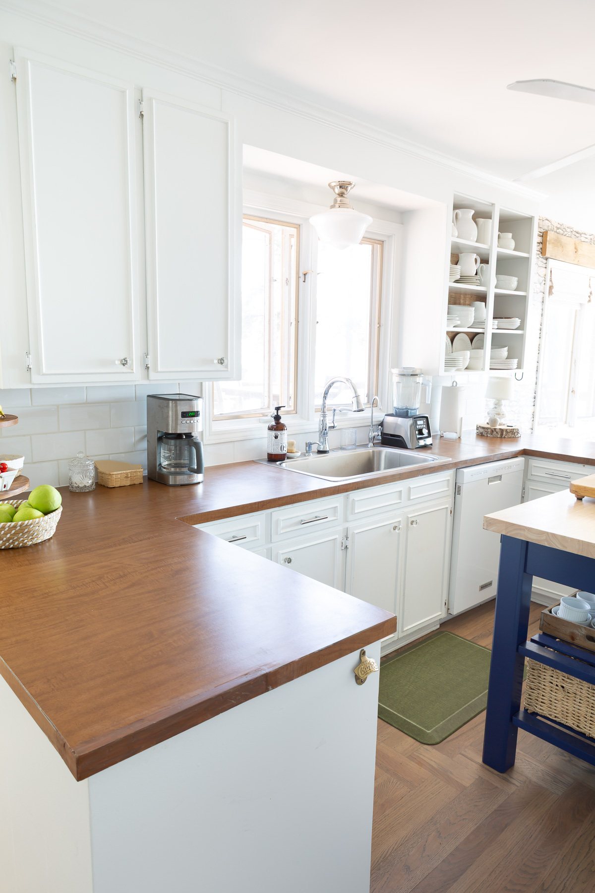 Looking a sink area in kitchen with white cabinets and brown Formica counters