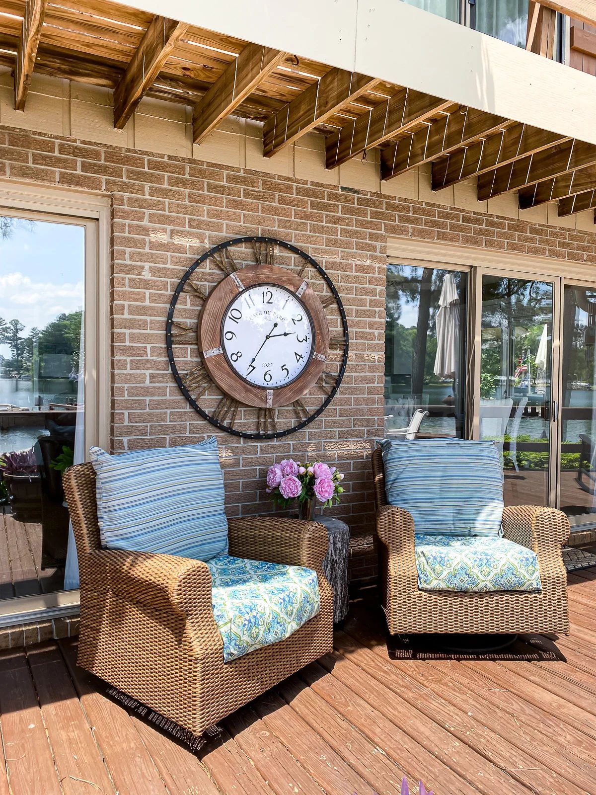 Woven deck chairs on deck with large wall clock on wall behind the chairs.