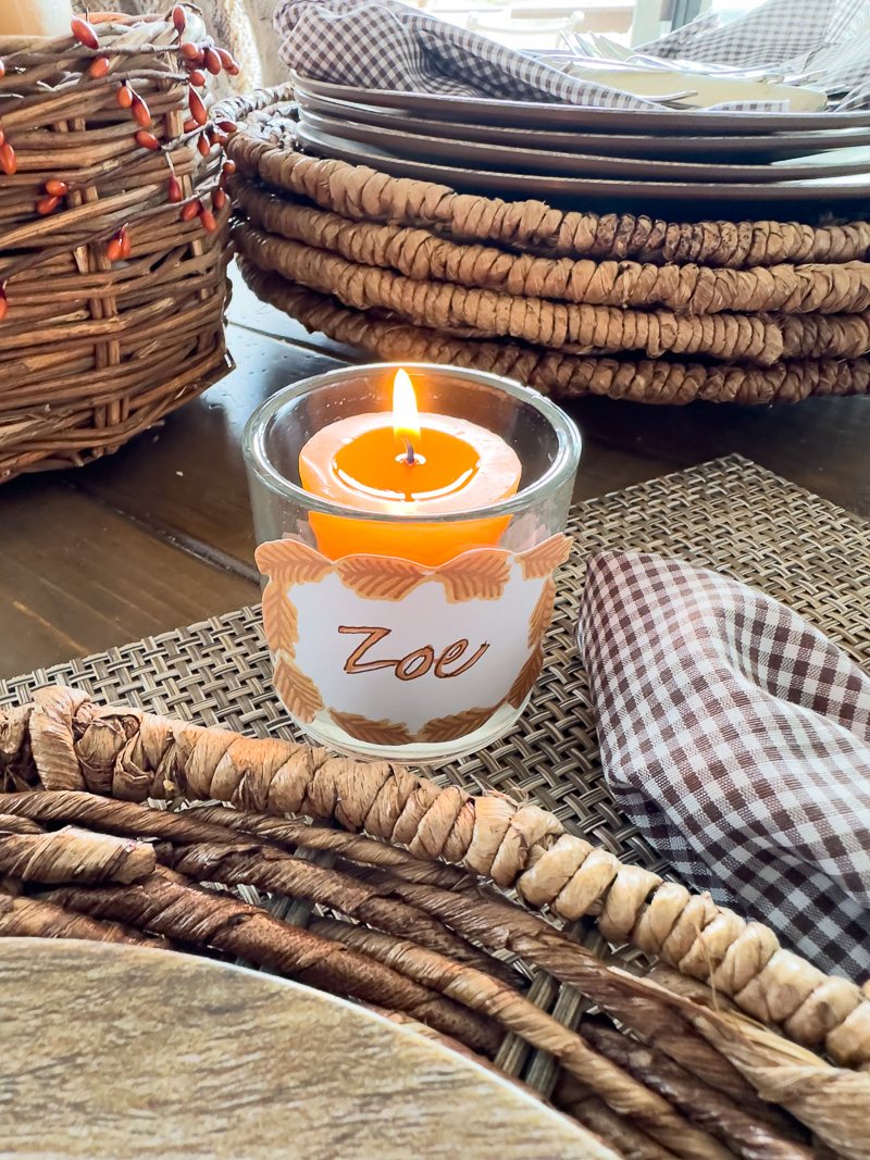 Burnt orange color votive candle in glass holder with free printable Thanksgiving place card hot glued to it.