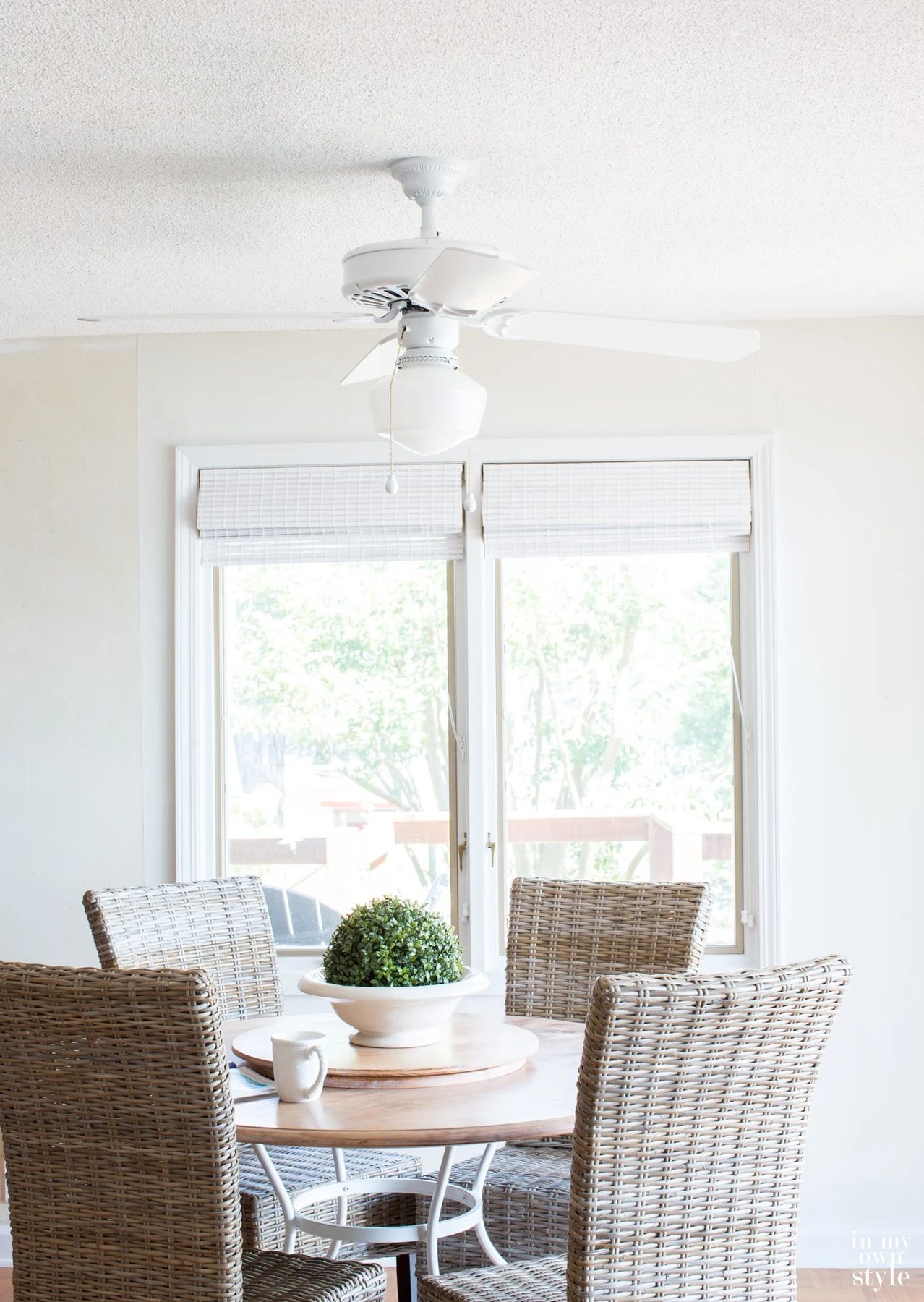 Photo of newly painted ceiling fan over a round dining table and wicker chairs.