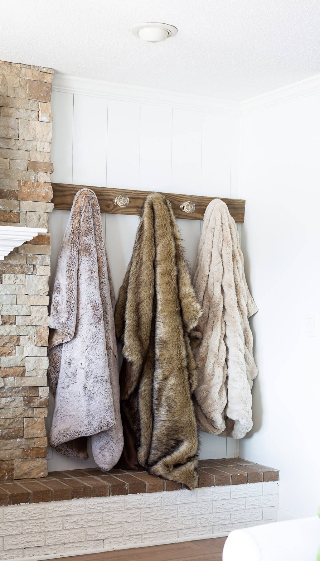 Blanket display ideas. 3 fur throws hung on a wall mounted throw blanket rack.
