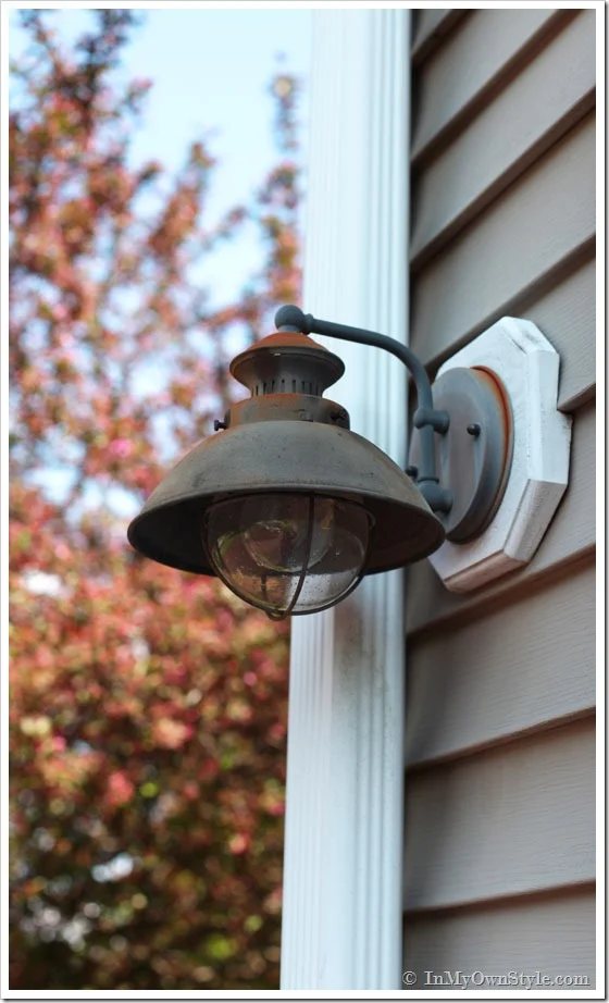 Rusty outdoor light fixture on side of a house.