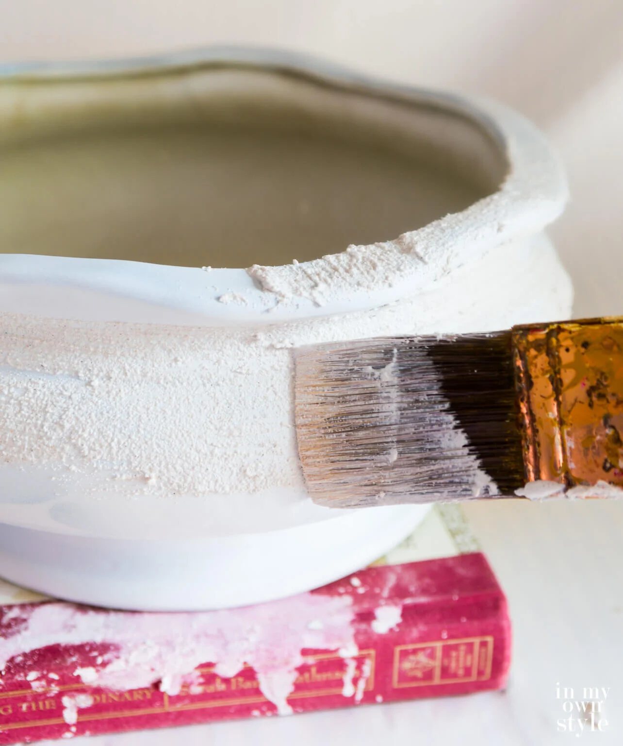 Brushing on stucco patch to create texture on a ceramic planter.