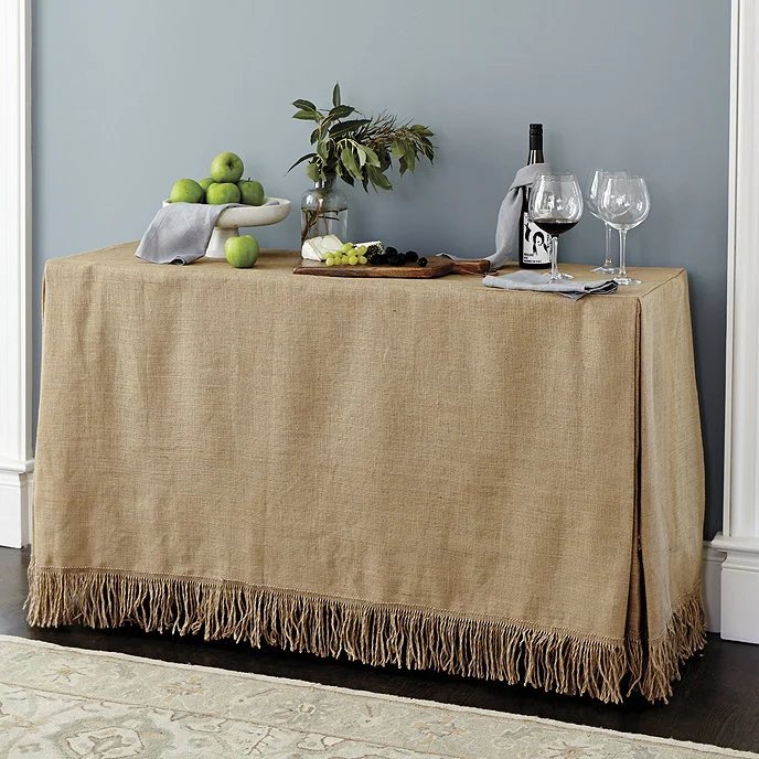 A burlap covered console table with pleated corners.