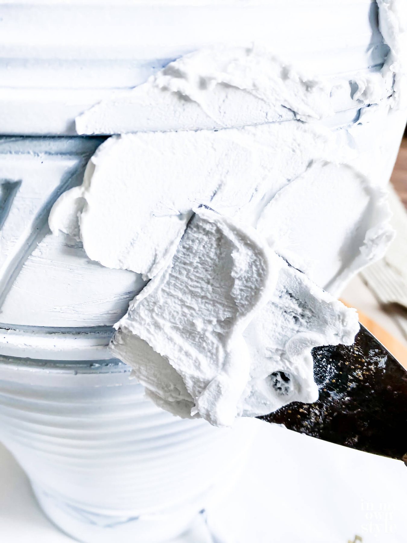 Close up of spreading Spackle over base of thrift store lamp.