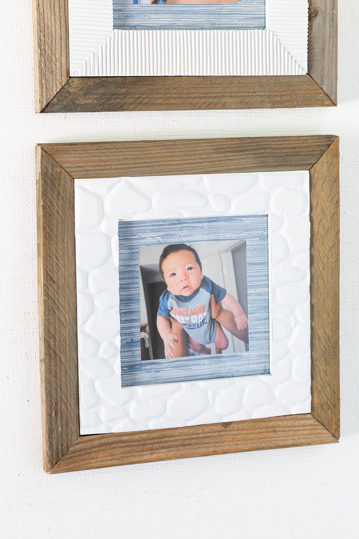 Scrap wood framed thrift store frame makeover idea that also uses wallpaper scraps and faux stone adhesive tile from the dollar tree.
