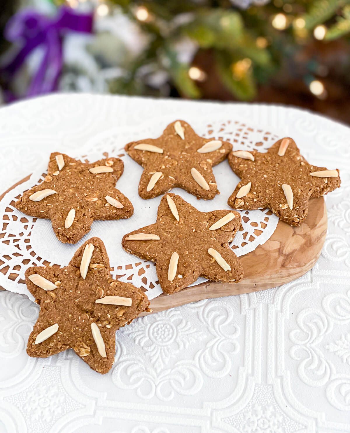 Vegan Christmas cookies on a doily in front of a Christmas tree.
