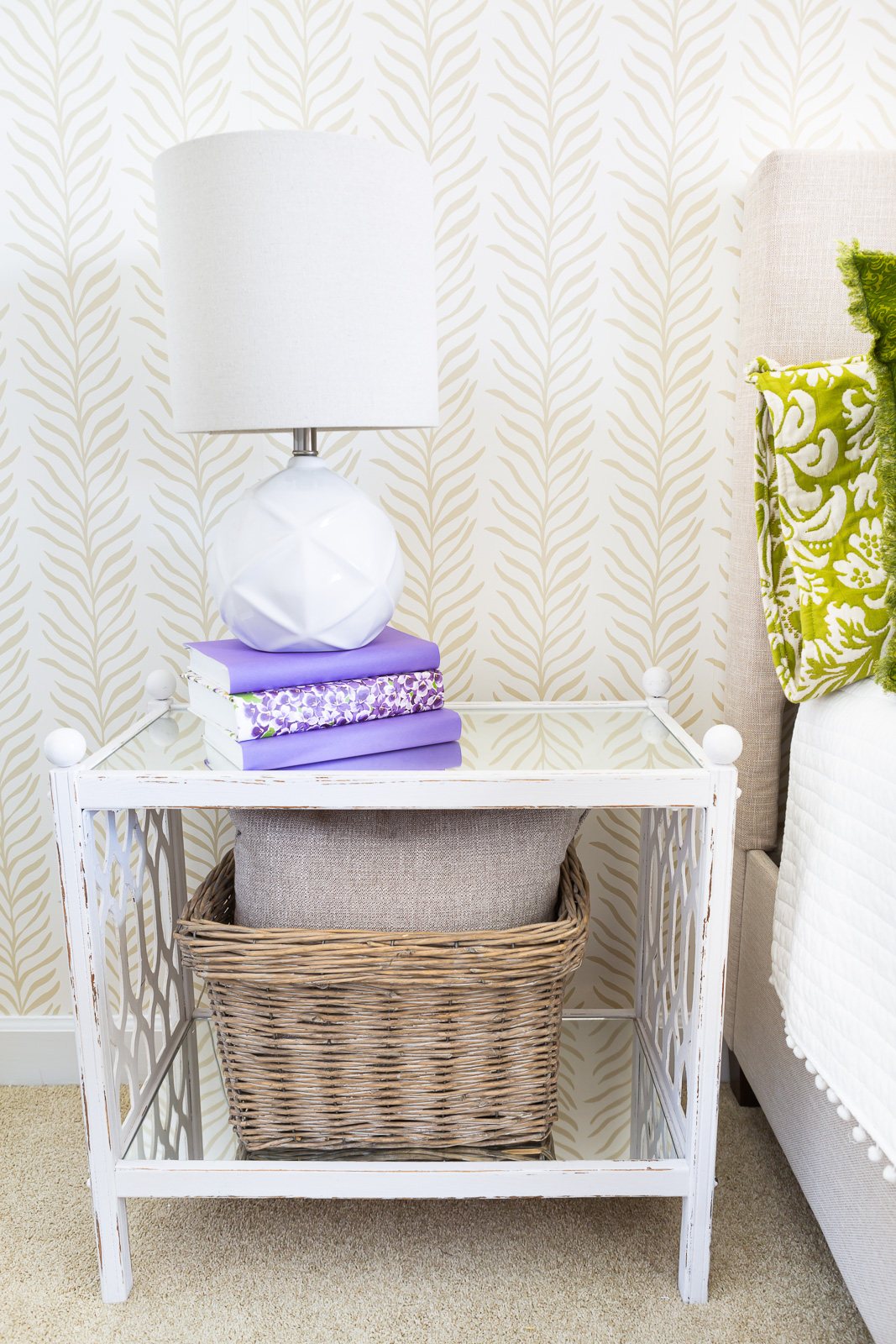 A white night table in a bedroom with an accent wall covered with a Love vs. Design wallpaper pattern called Vine Thread.