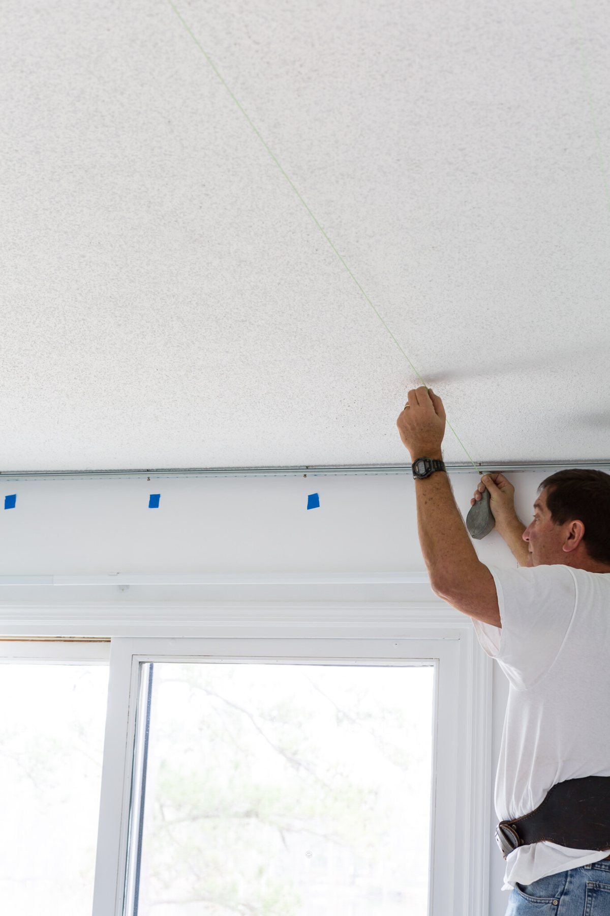 Snapping a chalk line on a ceiling to install a plank ceiling.