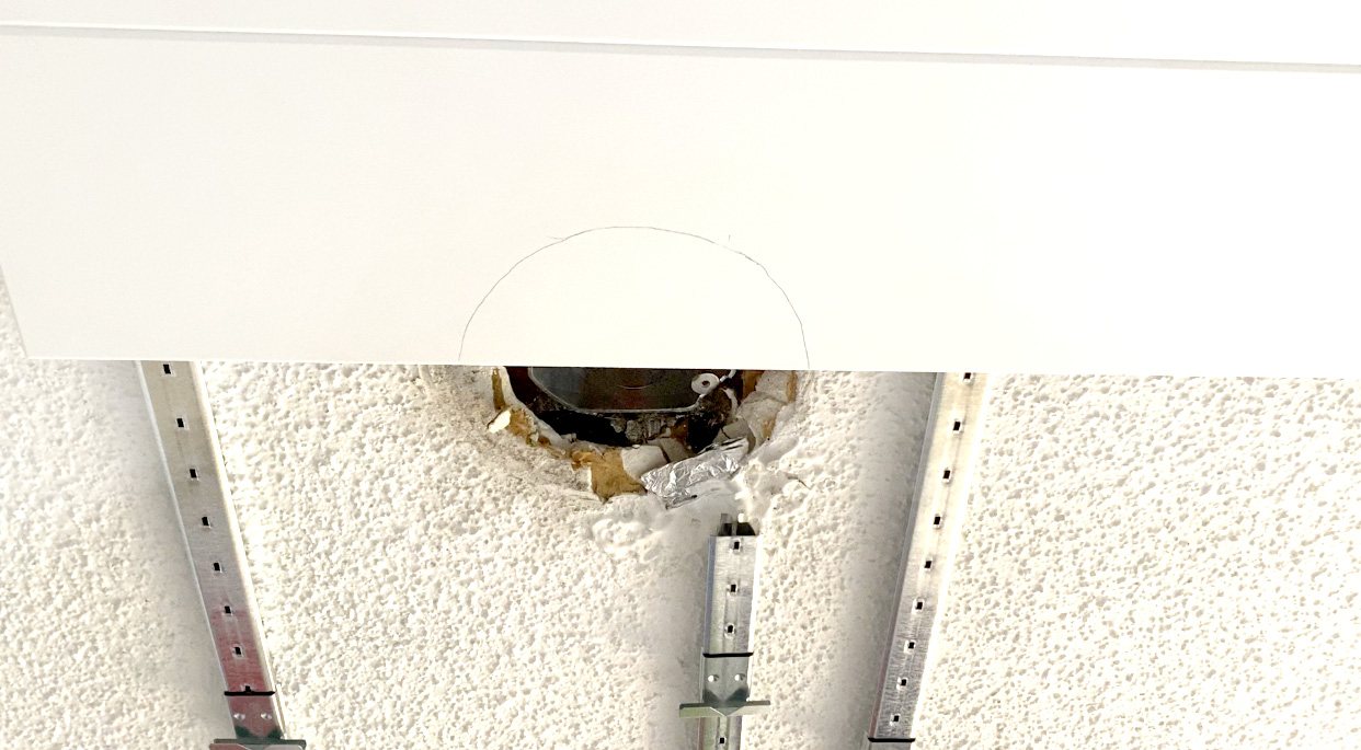 Close up shot of how to cut ceiling planks around light fixtures.