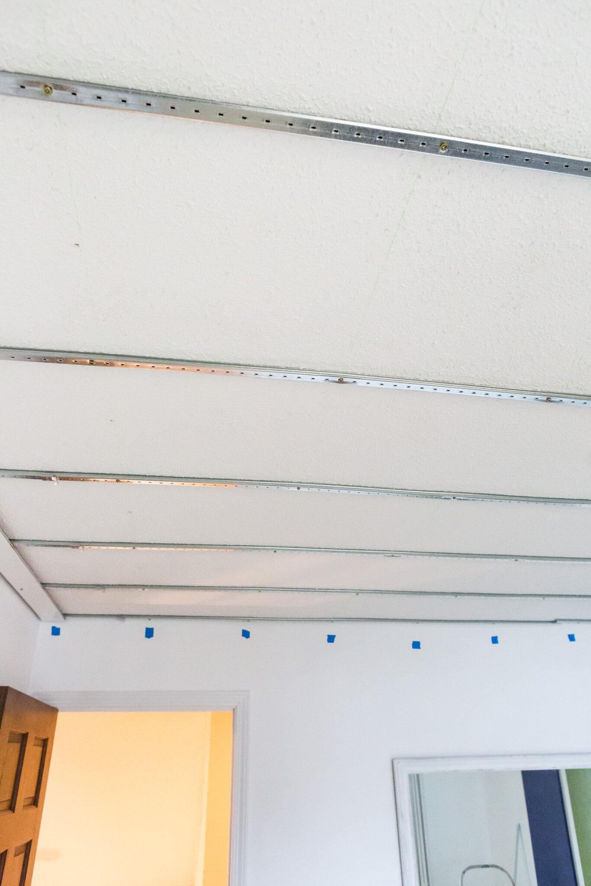 Covering a ceiling using Armstrong Easy Up tracks and clips. Once tracks are up, snap-on clips are used to attach planks.