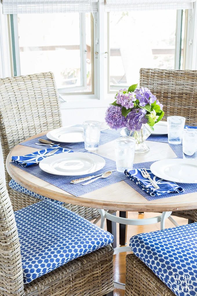 Dining table and chairs with blue and white chair seat cushions.