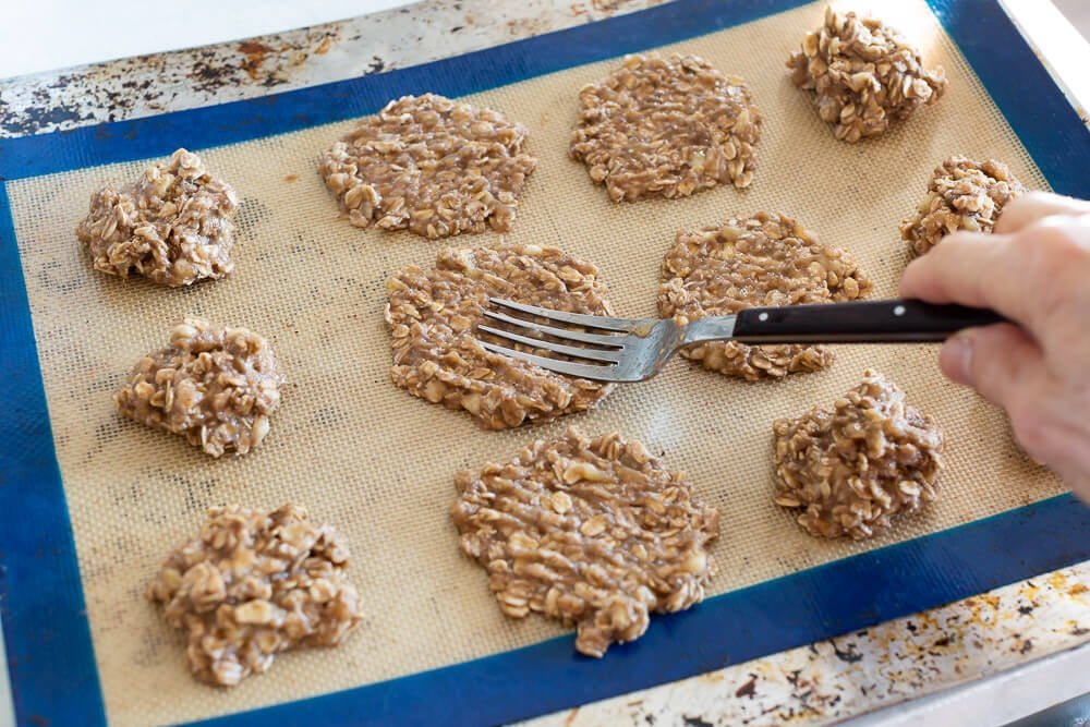 Flattening banana oatmeal cookies on baking sheet with a fork