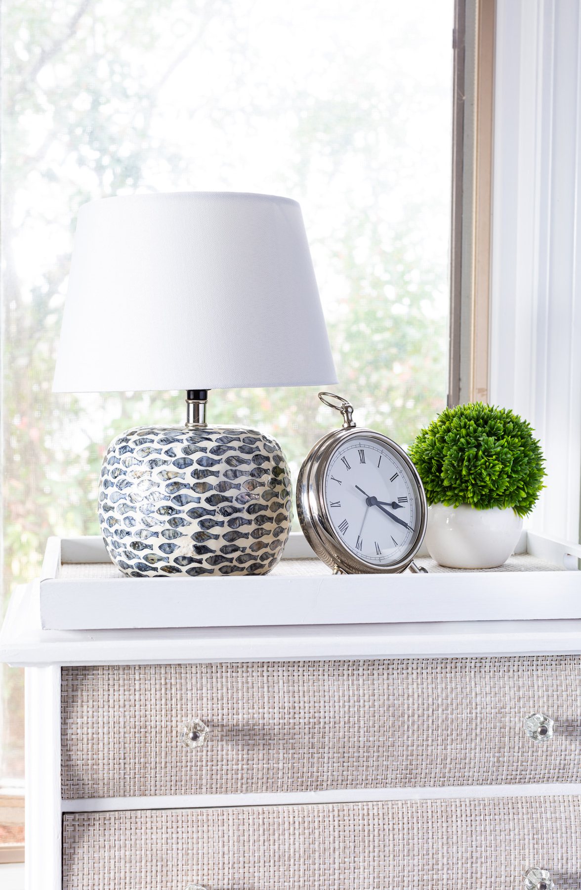 table lamp on night table with clock and greenery