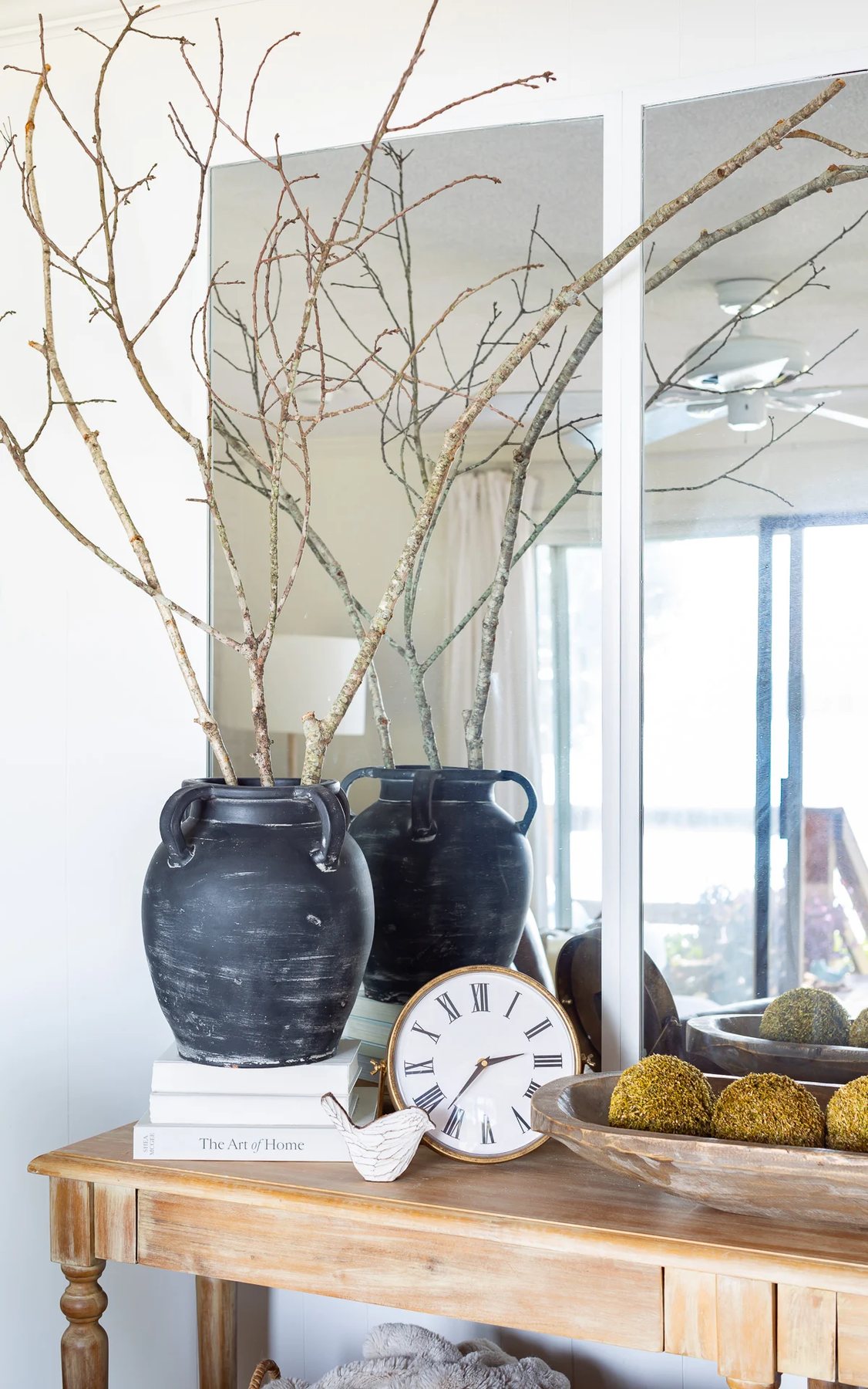 Black terracotta vase on stack of white books on a console table.