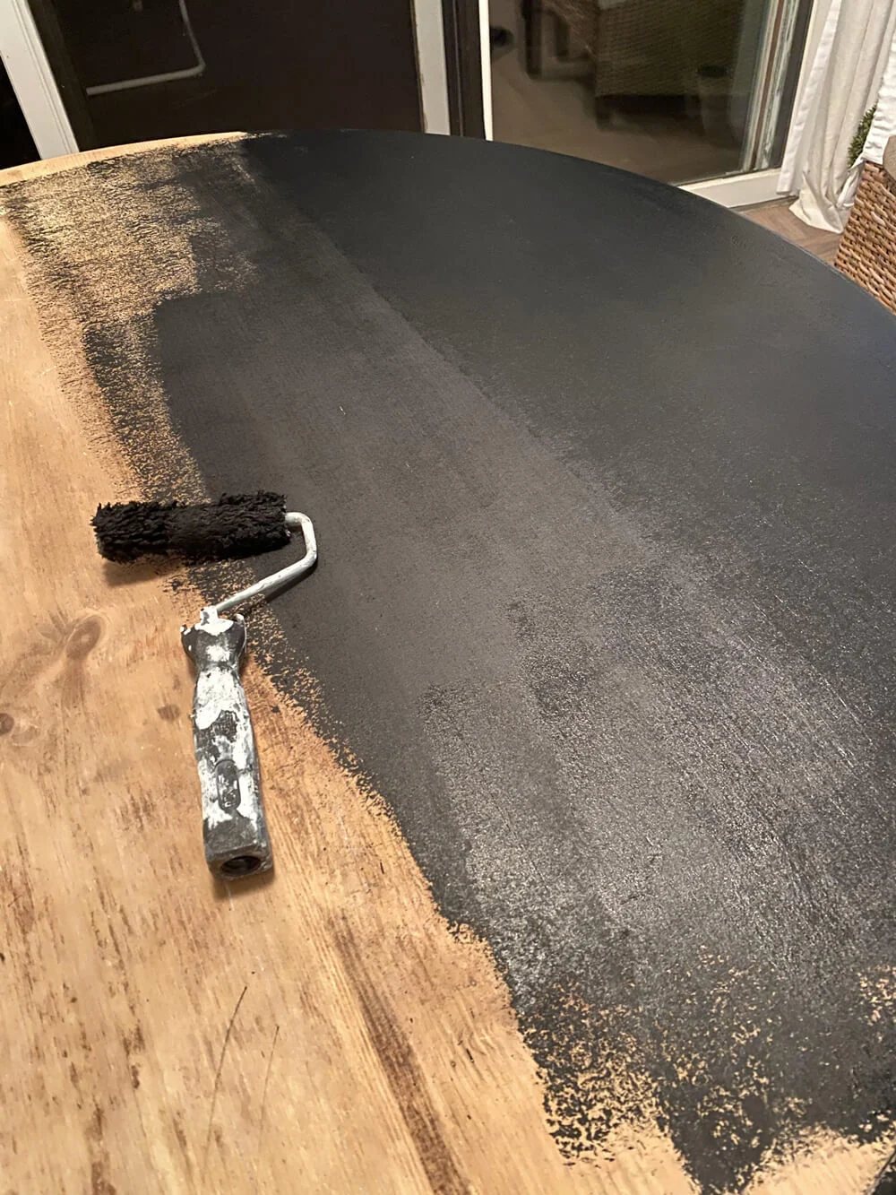 In the process of paint a round wood dining table with black base coat layer.