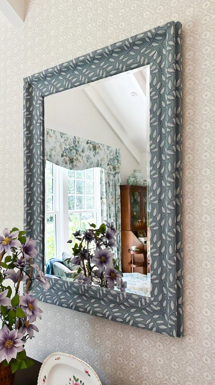 textured woven fabric covering the frame of a mirror in a bedroom
