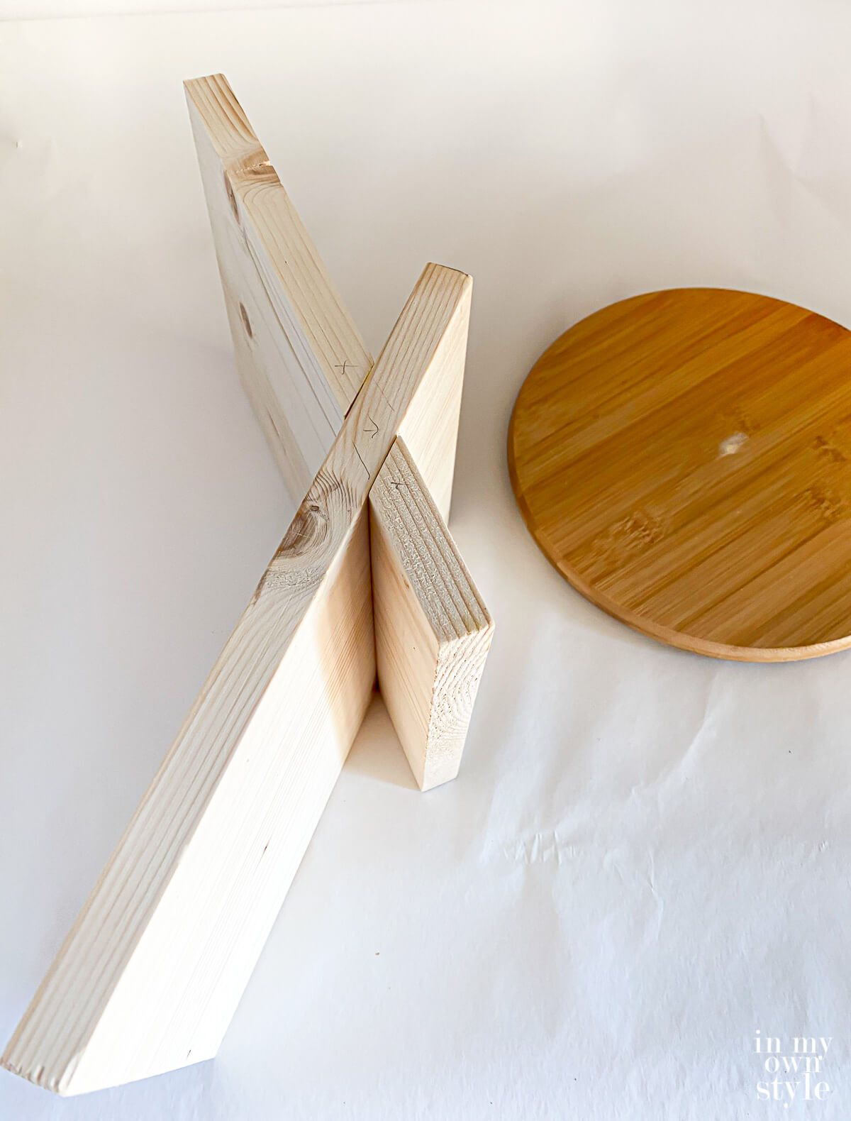 unpainted x shape book stand after being assembled. Shown on its side to see how to put together.
