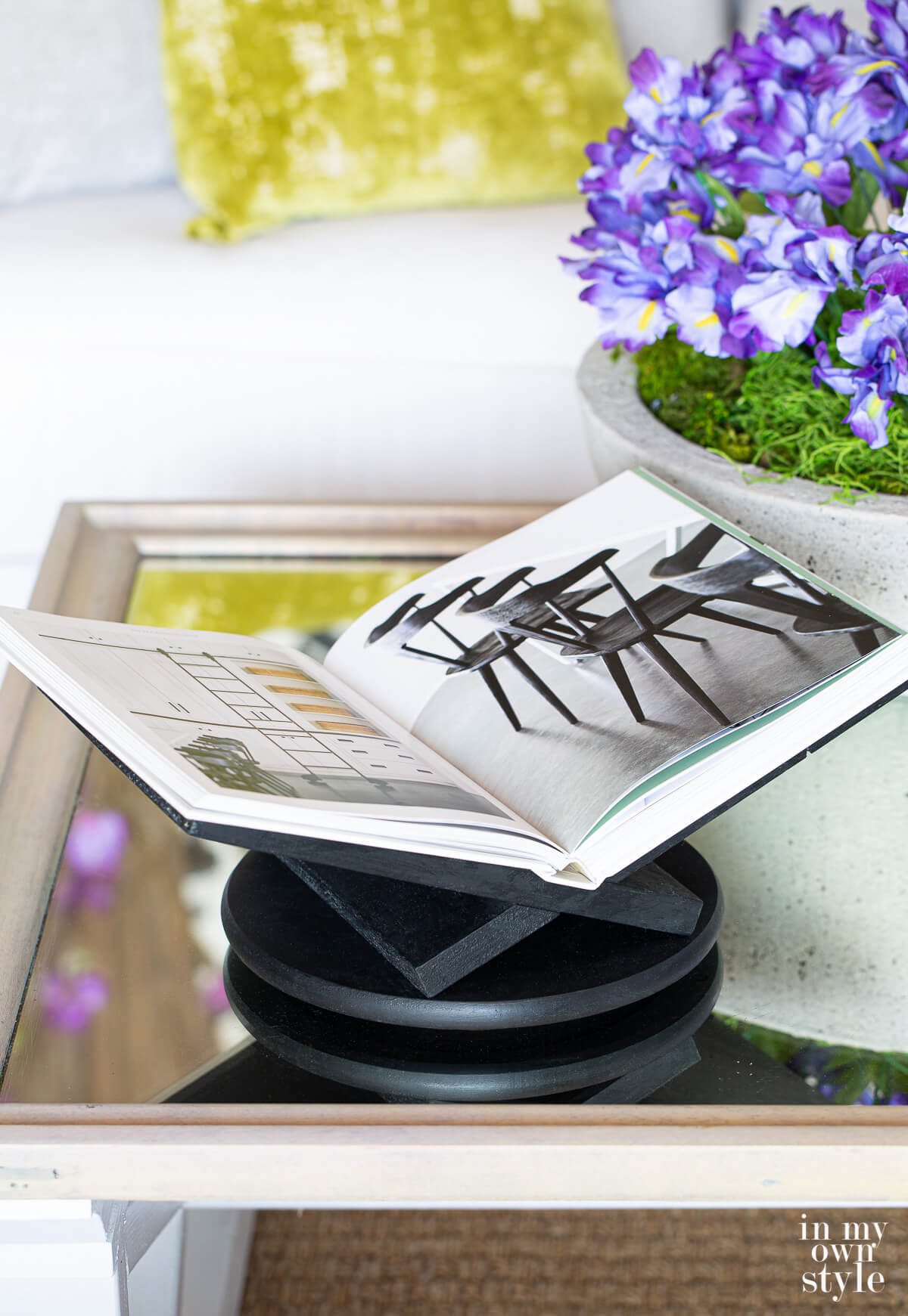 black painted x shape open book holder with book on coffee table.