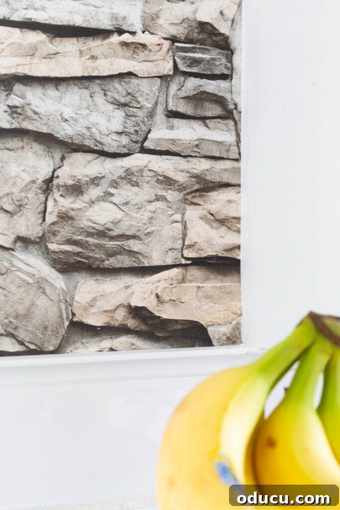 Unveiling Our Open Kitchen Wall 14 An even closer detail of the faux stone wallpaper on the kitchen's accent wall, emphasizing its texture and the natural color variations that give it a realistic stone appearance.