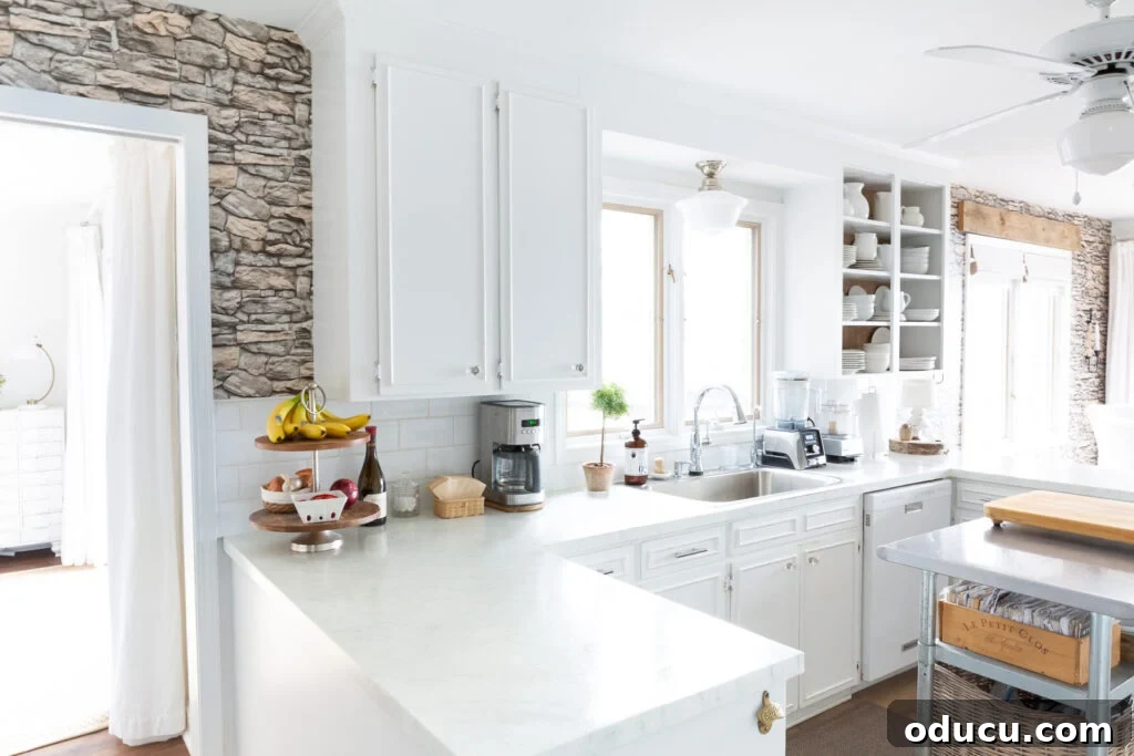 Unveiling Our Open Kitchen Wall 17 A comprehensive wide view of the kitchen and dining area's long wall, showcasing the harmonious blend of grasscloth wallpaper on the open shelves and the stacked stone wallpaper on both ends, creating a unified and textured design.