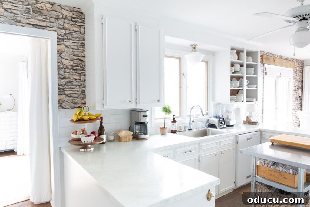 Unveiling Our Open Kitchen Wall 8 A wide view of the cohesive long wall in the kitchen and dining area, now beautifully unified with faux stacked stone wallpaper on both ends, extending from the hallway to the lakeside deck.