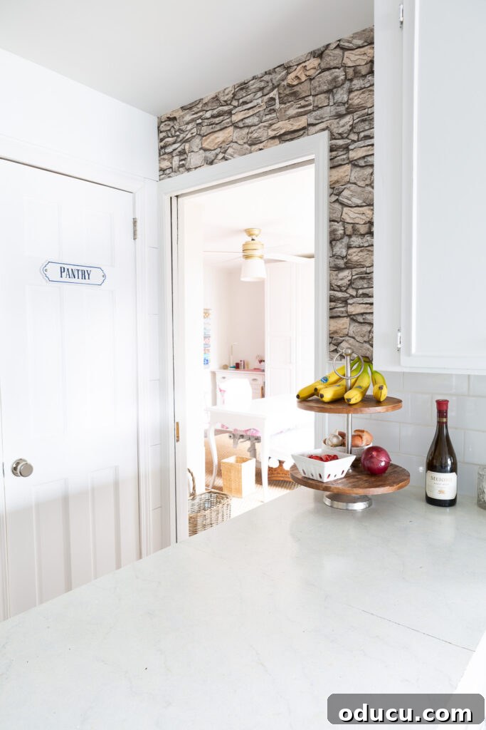 Unveiling Our Open Kitchen Wall 10 The kitchen's accent wall, adorned with faux stone wallpaper, now brightly illuminated with natural light flowing unobstructed into the adjacent multi-purpose room, previously an office.