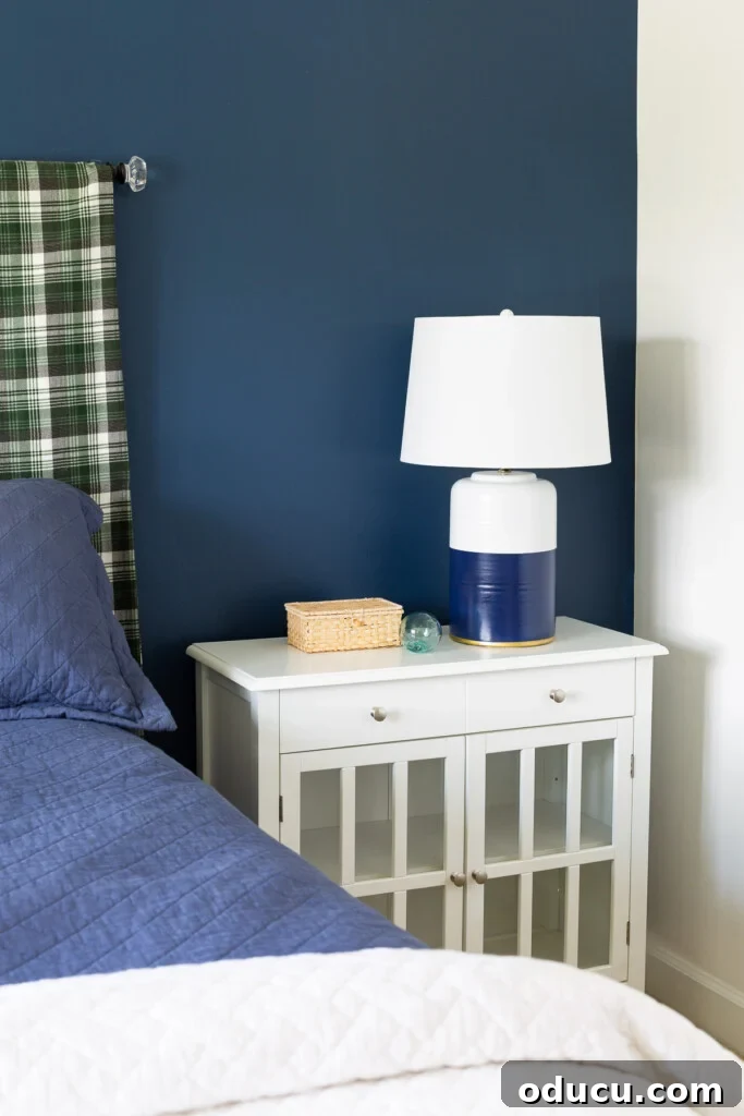 Blue and white bedroom with painted table lamp on nightstand. A thrift store lamp transformed to look like a high-end designer piece, now illuminating a cozy bedroom.