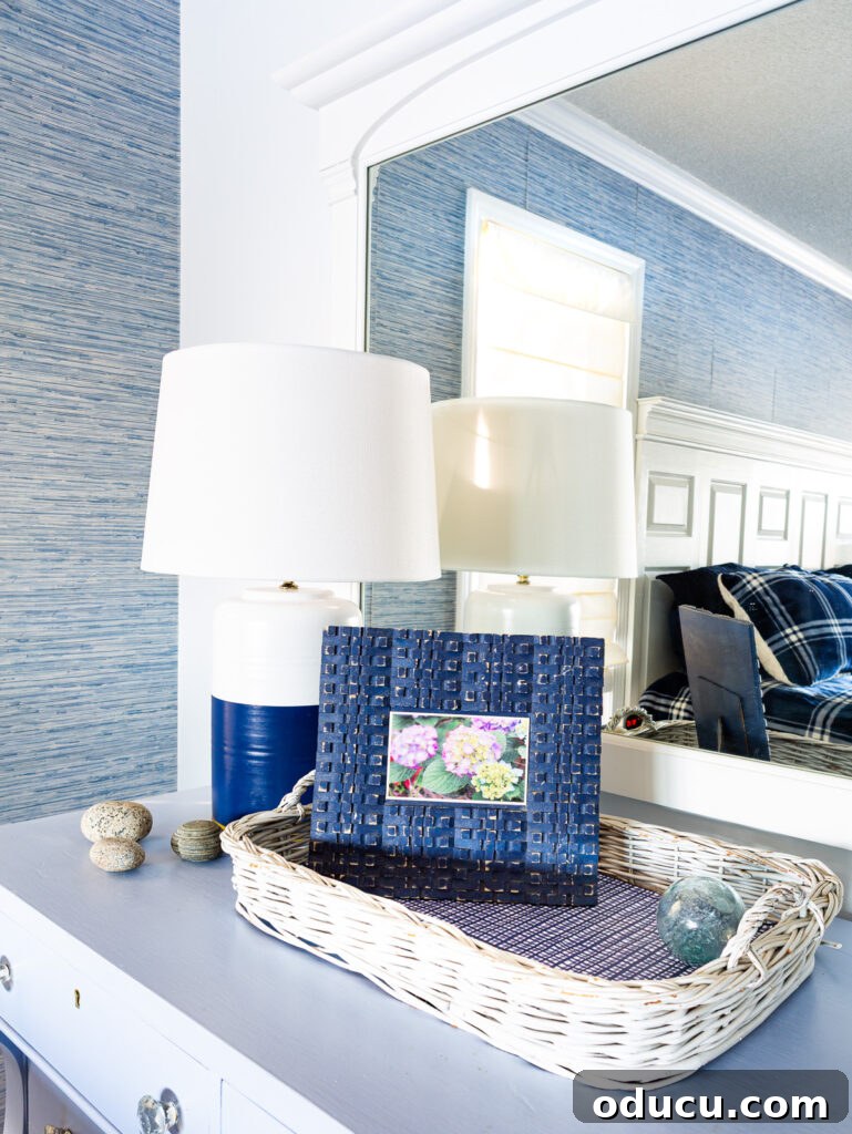 Blue and white lamp and blue picture frame on a blue dresser in a bedroom. The swapped thrift store lamp now adds a vibrant touch to the main bedroom.