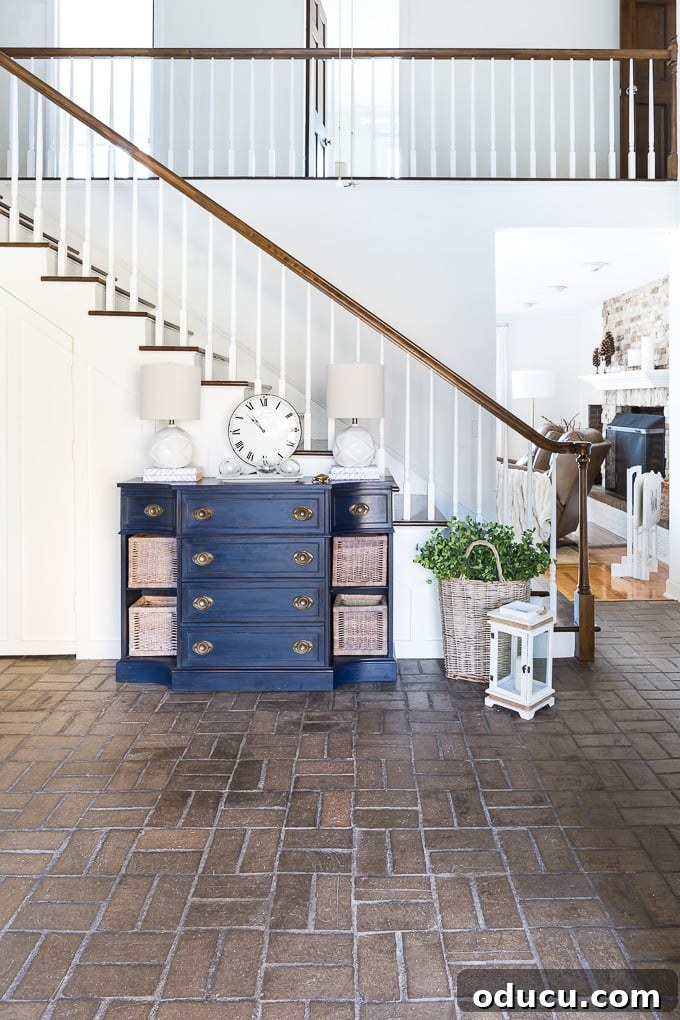 Looking from entryway of house into brick floored foyer. The blue sideboard, originally in the foyer, proves too small for the grand new space.