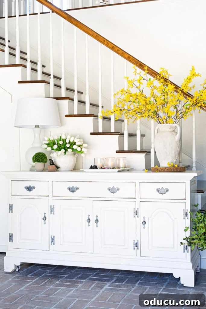 White dresser in foyer decorated for spring. The white dresser now perfectly anchors the grand foyer, proving its worth in a new setting.
