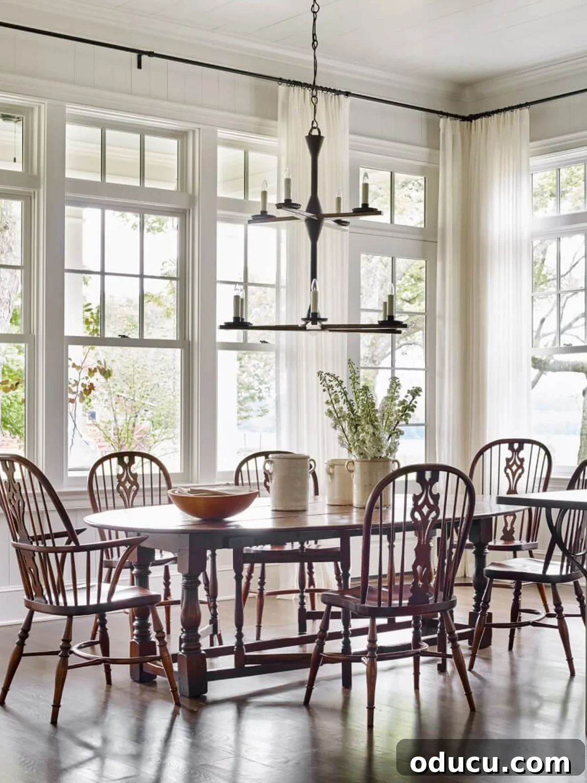 Fashion Field Notes: 233 2 Elegant open dining area featuring Windsor chairs around a stylish dining table, bathed in natural light, evoking a sense of classic comfort and modern farmhouse aesthetic.
