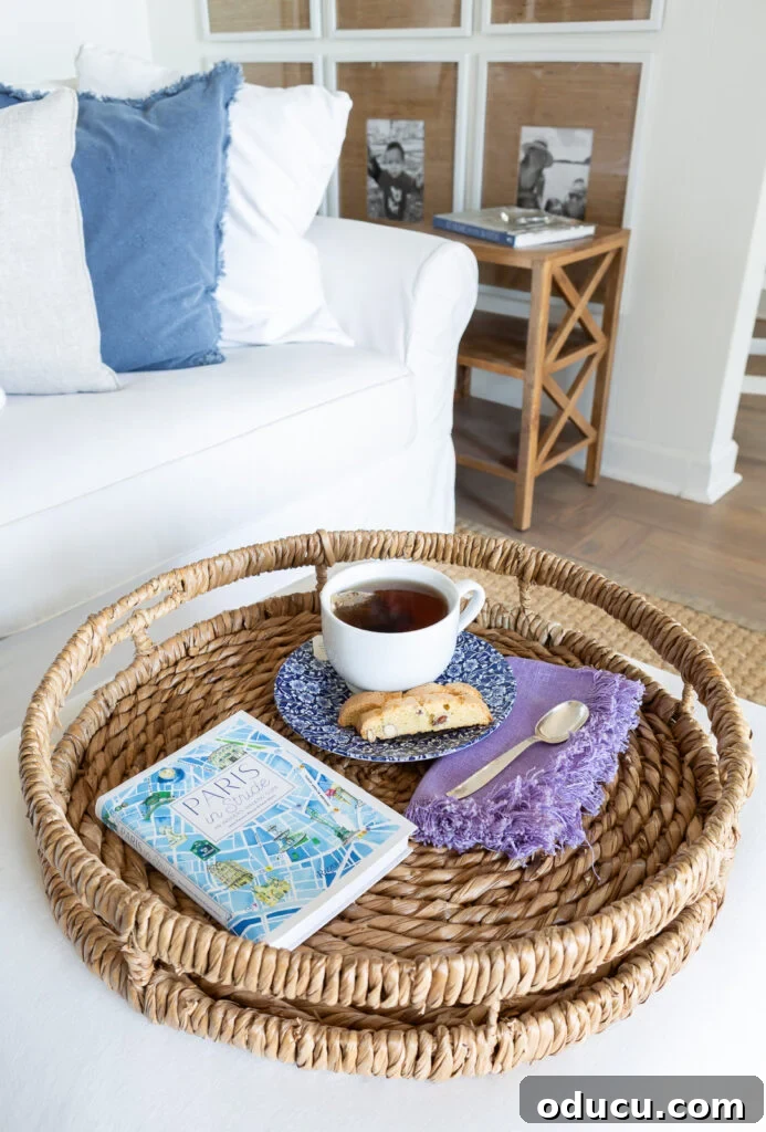 Looking down at a round rattan tray holding a cup of tea, napkin and spoon, a biscotti and a book.