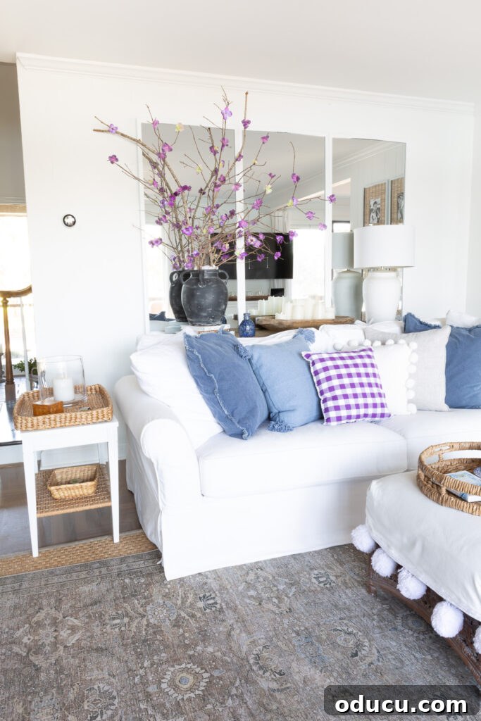 White sofa on mirror wall in living room with blue and purple toss pillows on it.