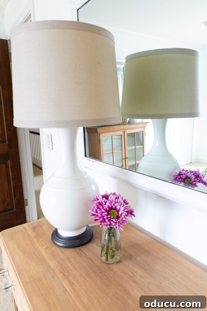 The Transformed Cabinets 12 A lamp and fresh flowers adorn the newly refinished wood cabinet in a guest bedroom, with a reflection of its matching top piece in the mirror