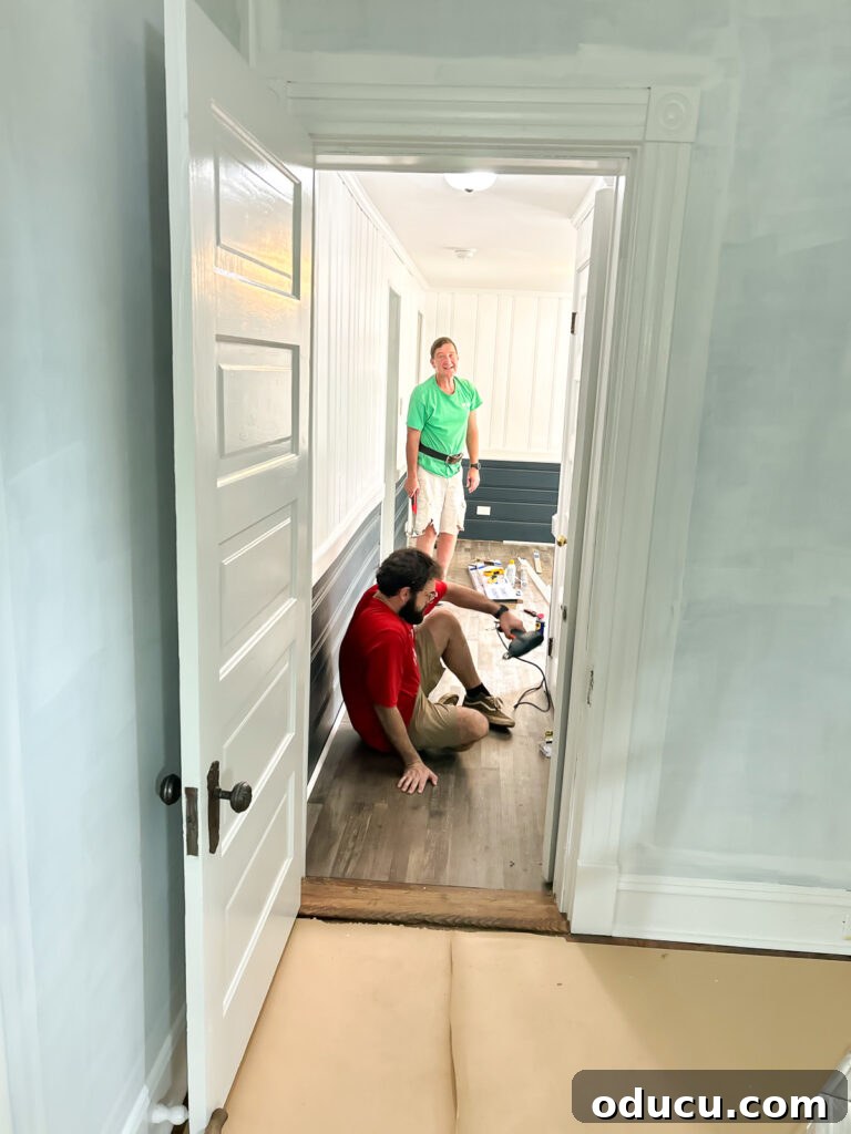 Another view of new flooring being installed in the sunroom, highlighting teamwork.