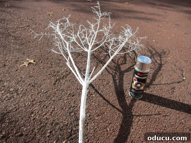 Applying silver spray paint to the branches Make Sparkly-Branches-using silver-spray-paint