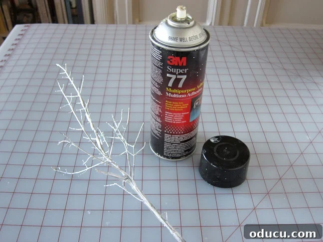 Applying spray adhesive for glitter Make snowy branches for holiday decorating