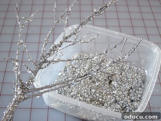 Sprinkling glitter onto the adhesive-coated branches How to make glitter tree branches for Christmas decorating or winter decoratting