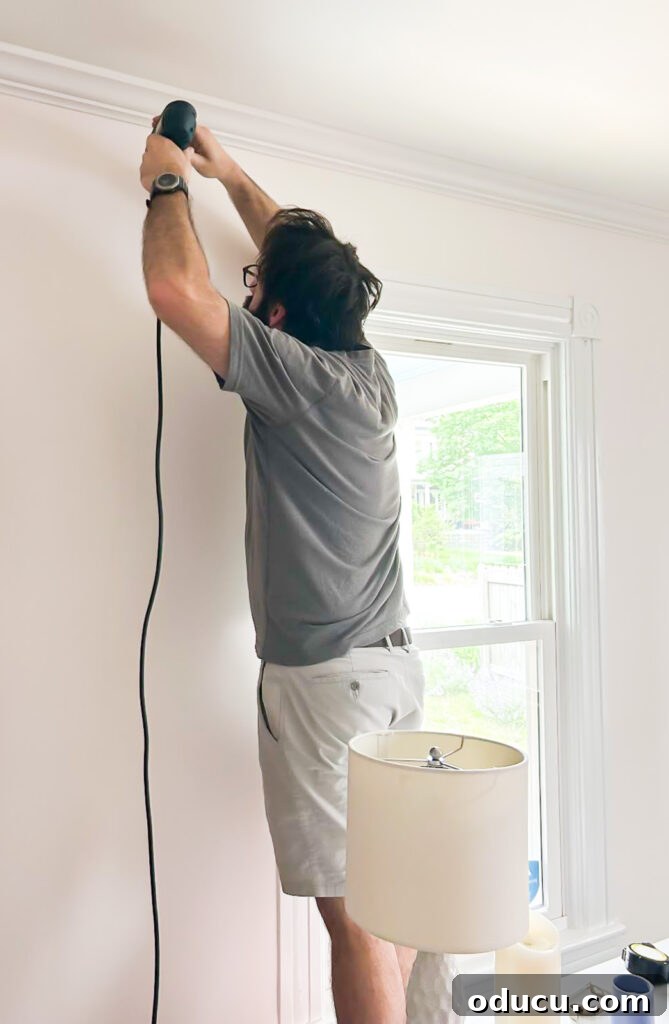 THY Curtains Adorn Every Space Beautifully 10 A man drilling precision holes in the wall, preparing to securely hang a curtain/drapery rod for the new window treatments.