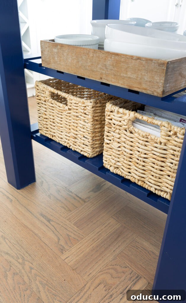 View of the bottom shelf on a small kitchen island, neatly organized with two decorative baskets.