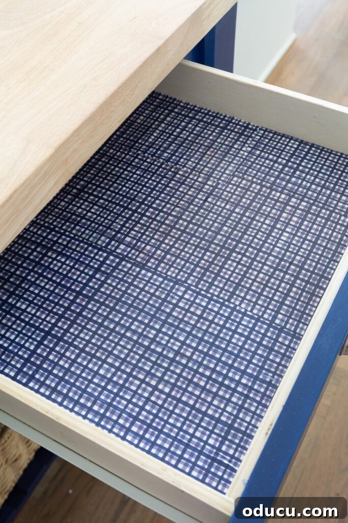 Lining a kitchen drawer with decorative gift wrap and sealing it with matte sealer for durability.