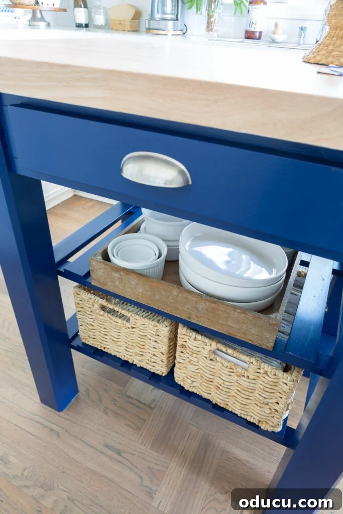Close-up of the painted kitchen work table island, showing its two adjustable shelves and a drawer for practical storage.
