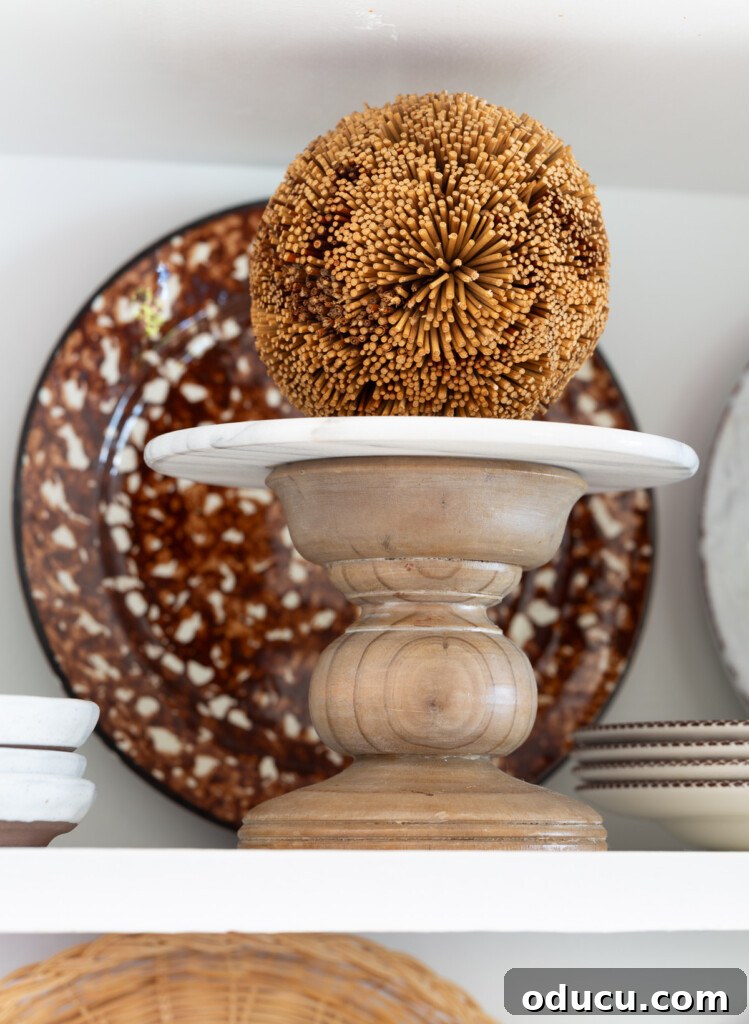 Fall Decor Reimagined 19 A small wood pedestal with a decorative fall colored orb on am open shelf in a kitchen.