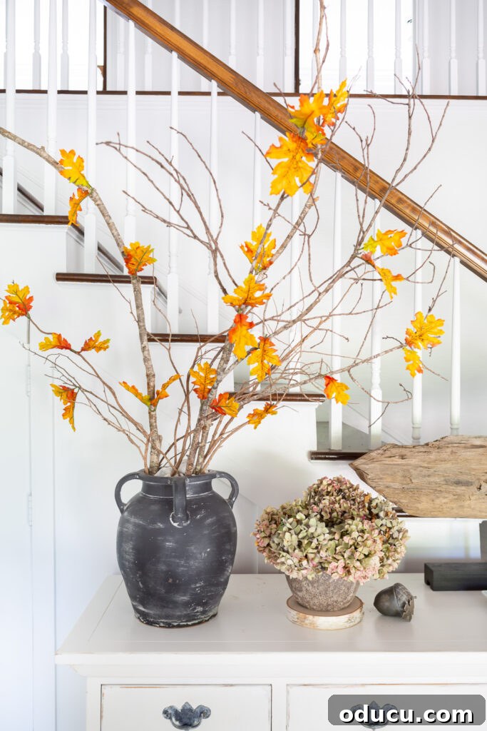 Fall Decor Reimagined 23 Single faux fall leaves added to real tree branches to decorate a home for fall.