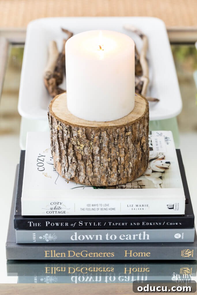 Fall Decor Reimagined 25 Books and candle on cut round a tree trunk on a coffee table.