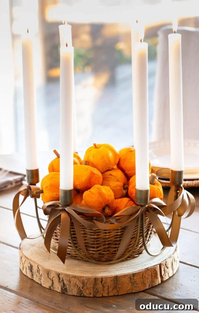 Fall Decor Reimagined 36 Antique Brass 6 taper candle centerpiece with brown ribbon bows added on wood slice on table. Center has basket filled with tiny paper pumpkins.