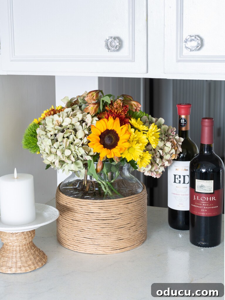 Fall Decor Reimagined 38 paper twist ribbon cord wrapped glass vase with fall flowers in it on a kitchen counter