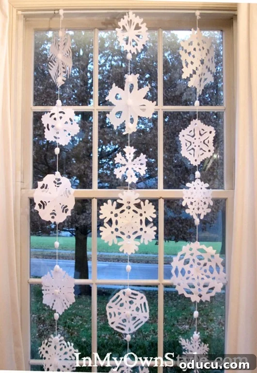 DIY Paper Snowflake Window Displays 3 Beautiful paper snowflakes gently hanging in a window, creating a festive winter atmosphere.